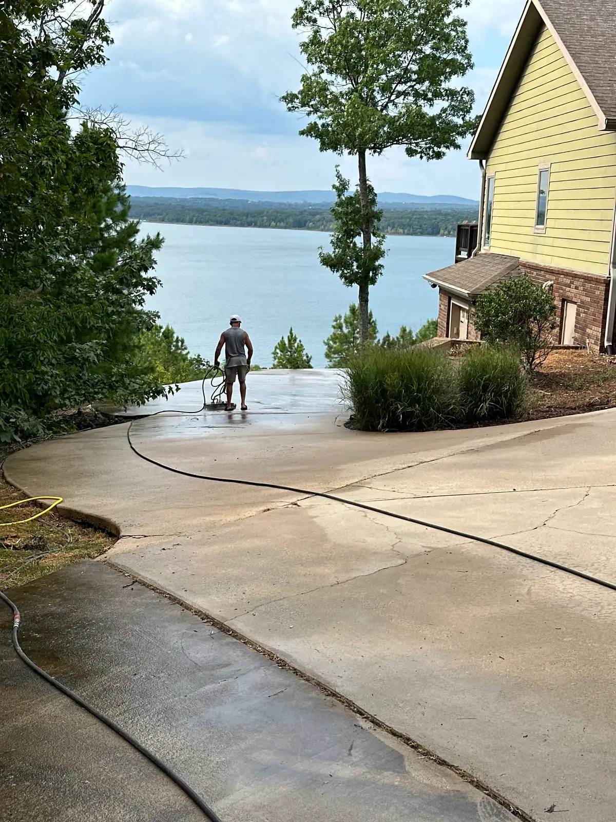 Natural State Soft Wash technician surface cleaning a large lakeside concrete driveway overlooking Greers Ferry Lake in Heber Springs, Arkansas