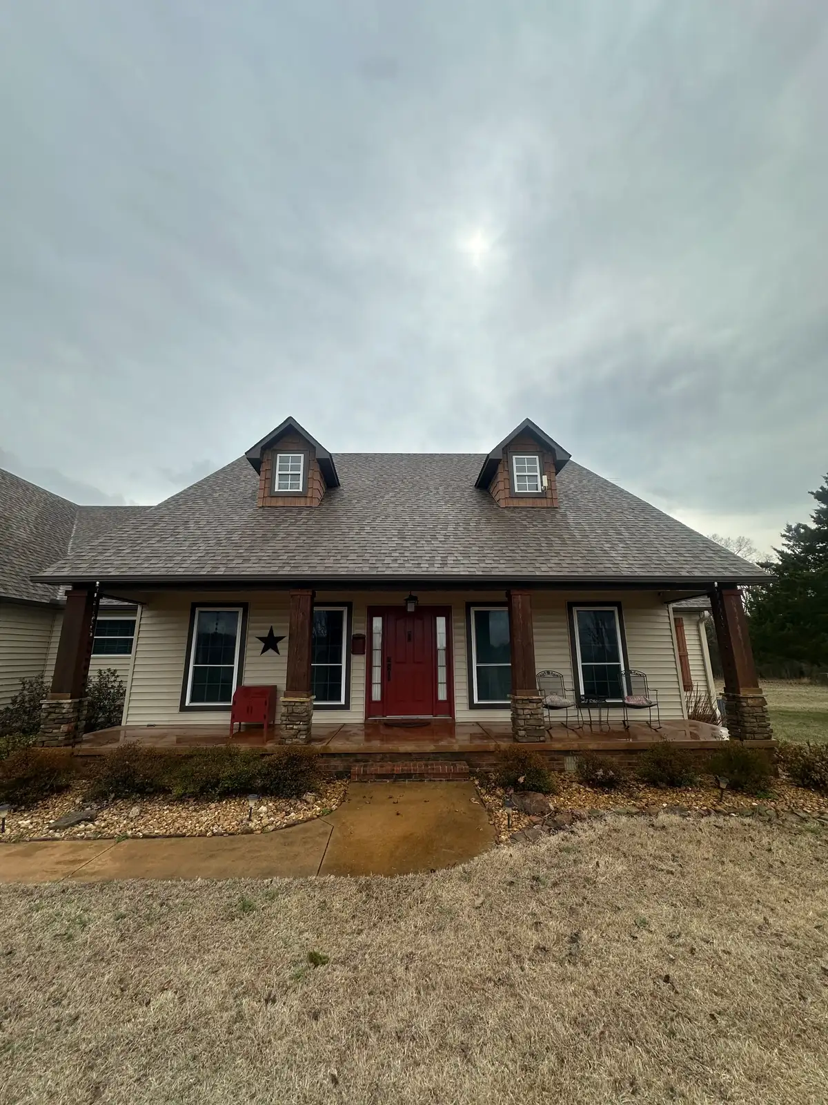 Before soft washing: front of a Central Arkansas home with dulled shingles, dingy vinyl siding, and a stained porch and walkway