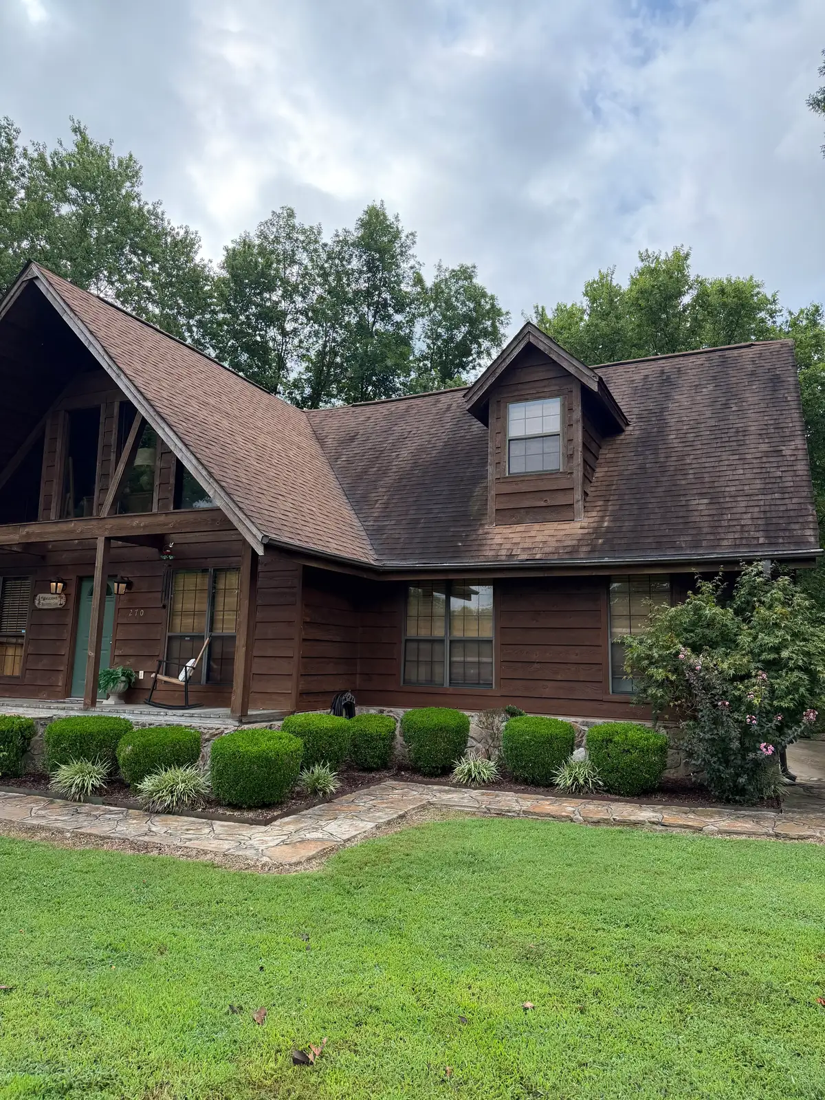 Log cabin in Heber Springs, Arkansas before roof washing — moss and algae on the roof